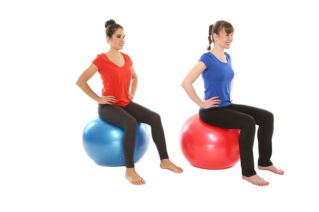 Dos mujeres sentadas sobre una pelota de yoga o fitball.