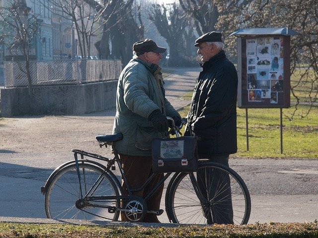 Una persona mayor con la bici se encuentra con otro y hablan.