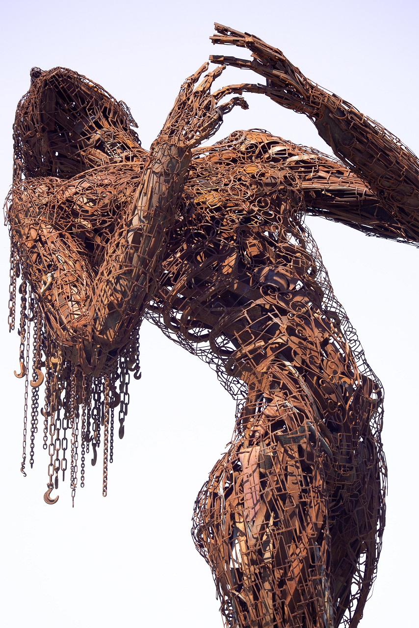 Escultura con cadenas que simulan a una mujer de pelo largo echándose para atrás. 