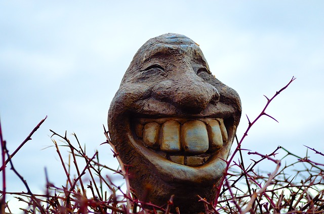 Escultura de una cabeza con una sonrisa amplia que enseña los dientes.