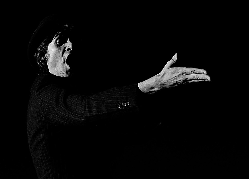 Actor declamando con brazo extendido. Imagen en blanco y negro.