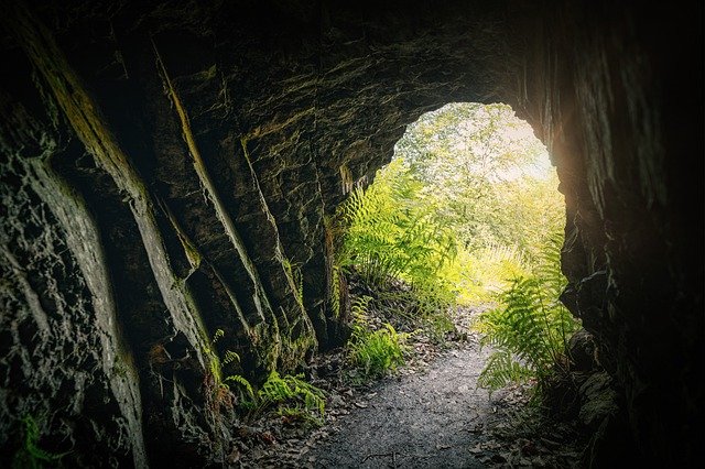 Fotografía de una gruta en una entorno natural con plantas y luz del sol