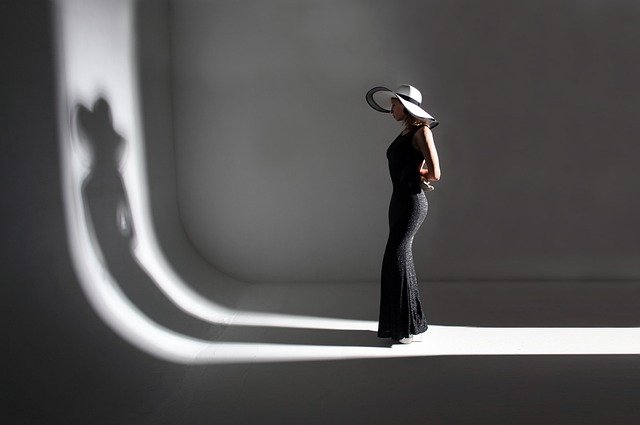 Fotografía de una sombra de mujer que se refleja en el suelo y en el espejo.