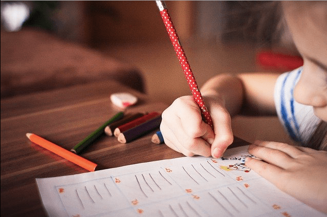 Foto donde se ve una niña con un lápiz escribiendo