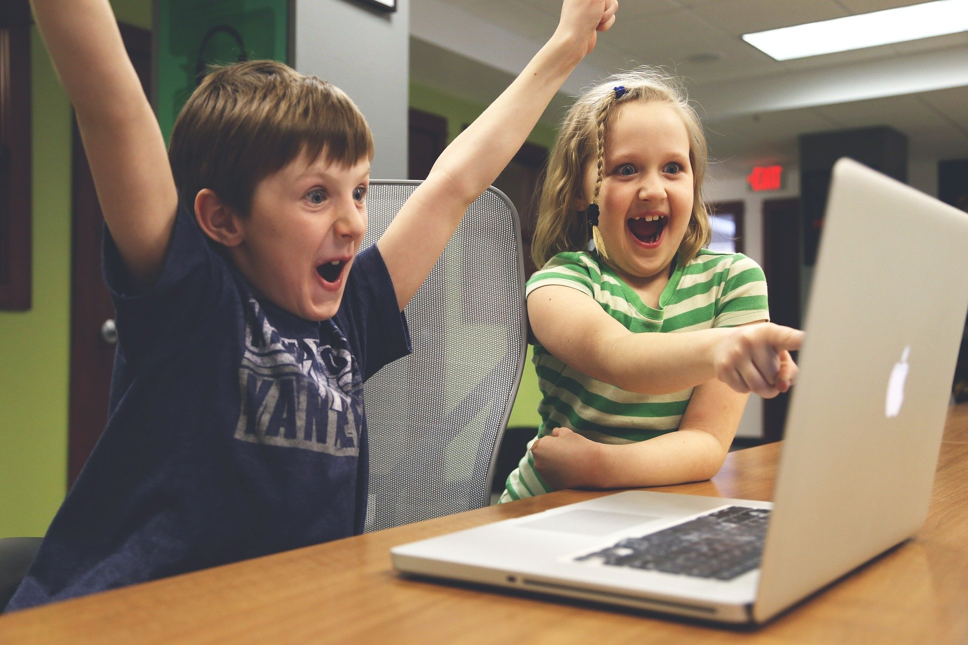 Niño y niña contentos mirando al ordenador 