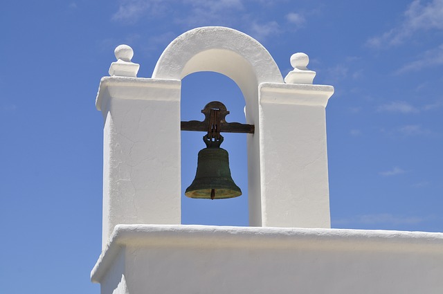 Fotografía de una campana situada en lo alto de una iglesia. 