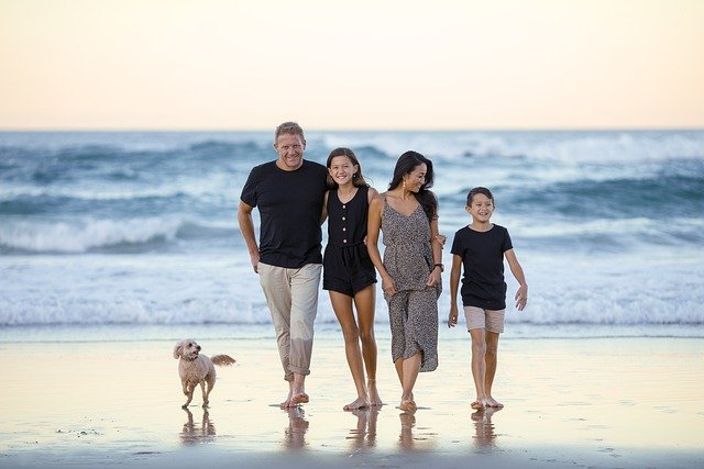 Una familia entera pasea por la playa de una forma muy cariñosa y complcie