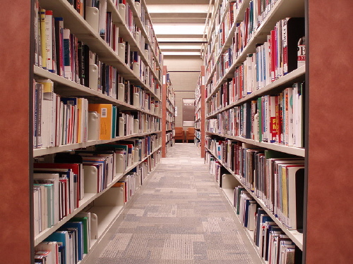 Pasillo de una biblioteca con multitud de estantes y libros