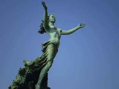 Estatua de mujer con los brazos abiertos.
