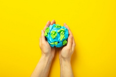Manos sujetando una bola de papel que emula el mundo
